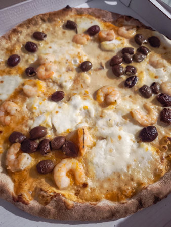 Savory pizza topped with shrimp, olives, and melted cheese, showcasing Italian culinary artistry. Captured in aosta, italy during novemberの写真素材