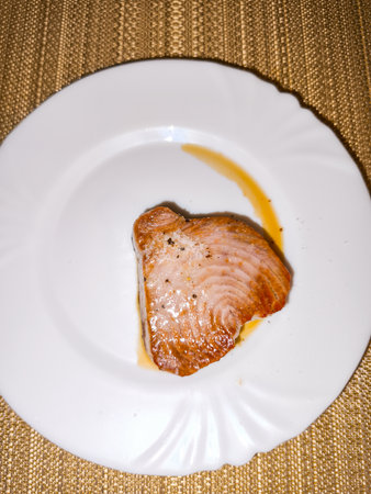 Seared tuna steak with sauce on elegant white plate
