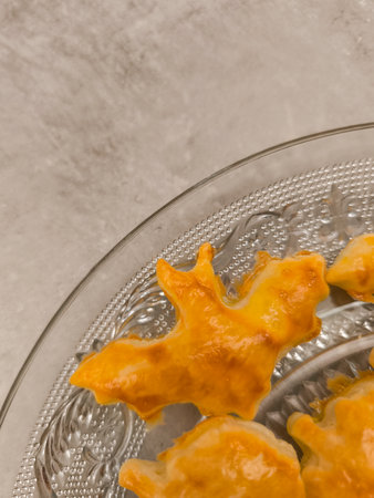 Bat shaped cookies resting on a glass plate for halloween party, copy space