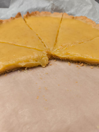 Delicious lemon tart showing missing slice on baking paperの写真素材