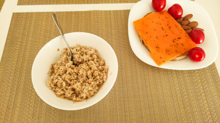 Healthy breakfast with oatmeal, cheese sandwich, almonds and cherry tomatoes