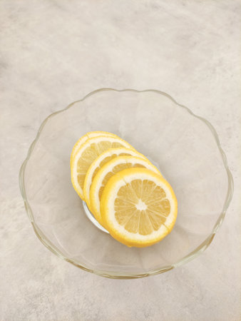 Lemon slices resting in a glass bowl on a marble countertopの写真素材
