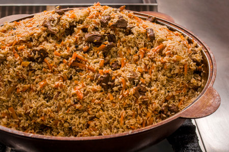 A large pot filled with traditional Uzbek plov pilaf, featuring fluffy rice, succulent meat, and...