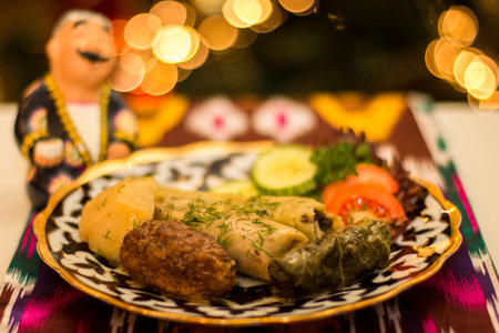 A beautifully arranged plate of Uzbek dishes dolma, showcases stuffed dumplings, fresh herbs, and vegetables, set against a colorful textile backdrop, highlighting the rich culinary heritageの写真素材