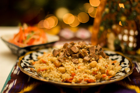 A beautifully arranged plate of Uzbek pilaf rice dish with succulent meat and chickpeas, surrounded...