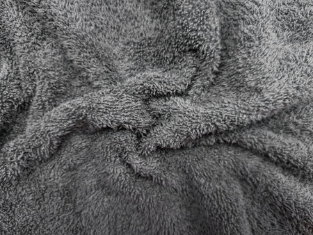 Close up view of soft, wrinkled gray microfiber fabric, creating a cozy and textured background that...