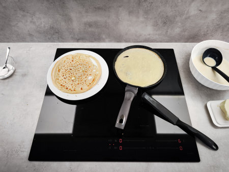 Cooking crepes on a modern induction cooktop for shrove tuesday celebration, maslenitsa or breakfast