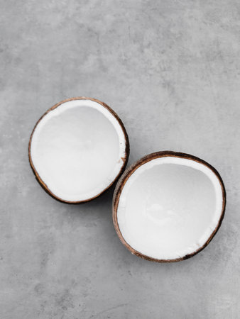 Two halves of fresh coconut resting on gray background. Copy space, bannerの写真素材