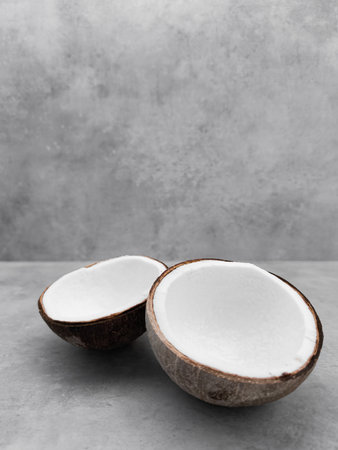 Two halves of fresh coconut resting on gray surface. Copy space, bannerの写真素材