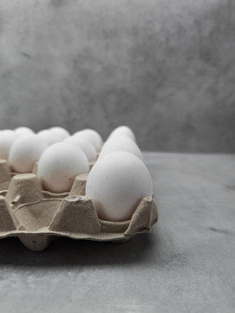 White eggs resting in carton on gray surface for easter or pancake dayの写真素材
