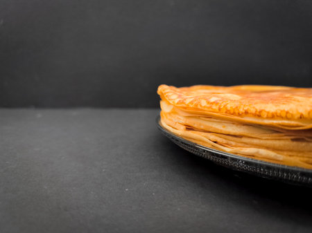 Stack of pancakes resting on a dark surface for maslenitsa or shrove tuesday with copy spaceの写真素材