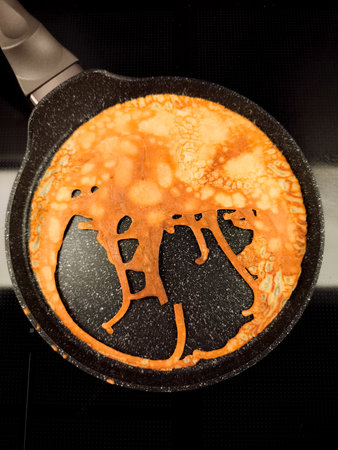 Bunny shaped pancake cooking in frying pan for maslenitsa or shrove tuesday breakfast