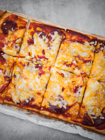 Delicious homemade square pizza with salami, peppers, and melted cheeseの写真素材