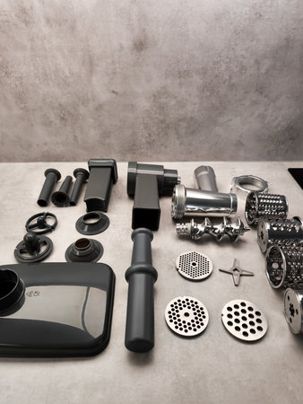 Disassembled meat grinder parts lying on kitchen counter