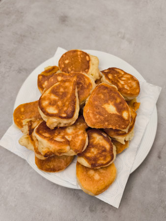 Small pancakes stacked on a white plate and absorbing excess oil on kitchen paperの写真素材