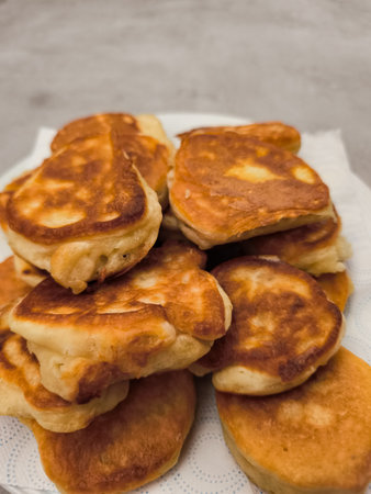 Golden pancakes stacked on white plate draining excess oil