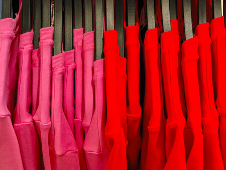 Pink and red sweatshirts hanging on clothes rack in prague storeの写真素材