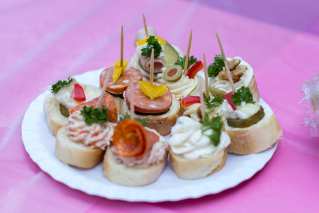 Wedding appetizers decorated with parsley on pink tablecloth