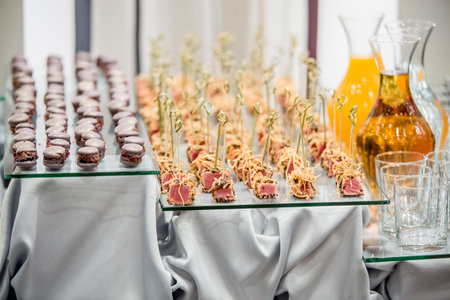 Catering appetizers displaying tuna and macarons on glass trays during wedding celebrationの写真素材