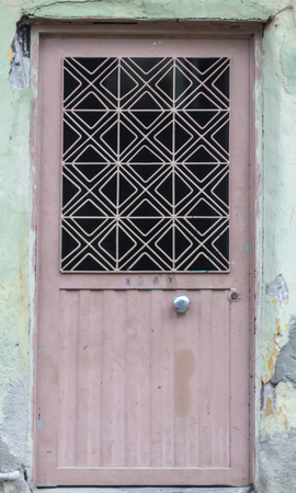 Front shot of traditional ornamented pale reddish metal doorの写真素材