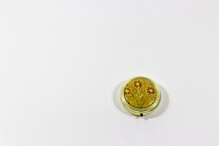 Ornamented shinny reflective single golden pill box with white backgroundの写真素材