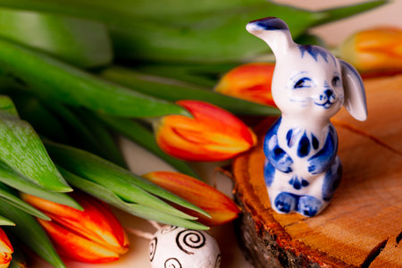Happy Easter! Decorated eggs, red tulips and porcelain rabbit on wooden background.の写真素材