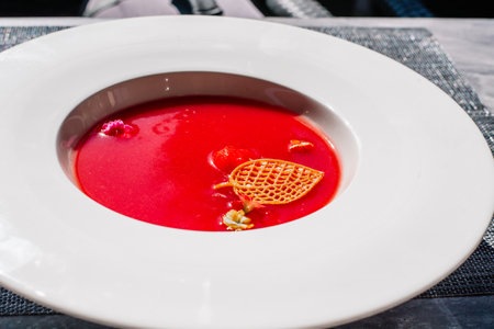 The red fruit, watermelon cold soup is poured into a light ceramic plate. Dishes stand on a light background.の写真素材