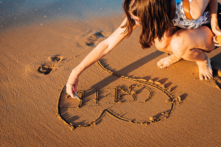 Young woman is writing Crete word into heart on the sand on the beach in the sunset.の写真素材