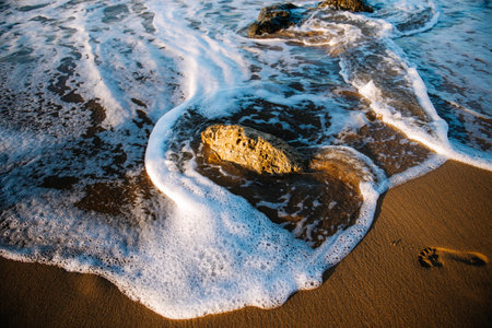 Directly above view of waves breaking on the shore at sunset. stone, waves, foam.