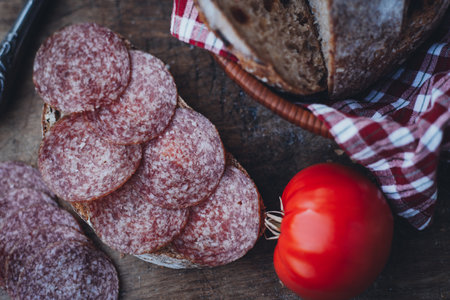 Italian sandwich with sliced salami. Sliced salami with bread and tomatoes