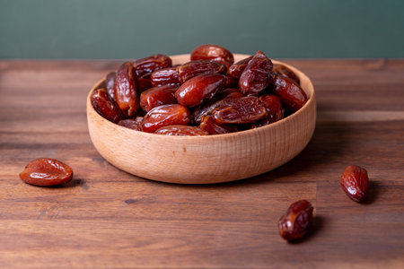 dried dates in a wooden pot on a wooden tableの写真素材