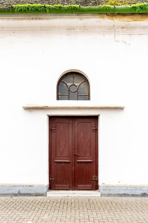 old wooden brown door in white wall of catholic churchの写真素材