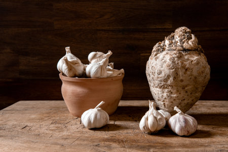 Organic garlic in pot and fresh celery root on rustic wooden table. Food background.