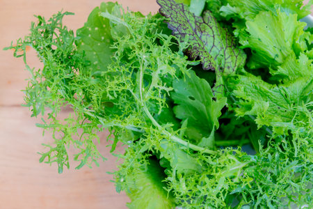 Fresh green lettuce leaves on wooden background. Healthy food concept. Top view.