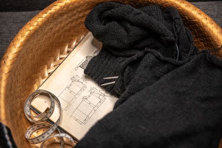Female hobby knitting. The beginning of the process of knitting a black sweater in a basket. The...