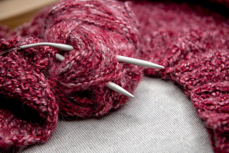 yarns, knitting needles and pattern sample on gray background. closeup