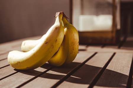 bunch of bananas on the dining table on the terrace with early morning sunlight shining throughの写真素材