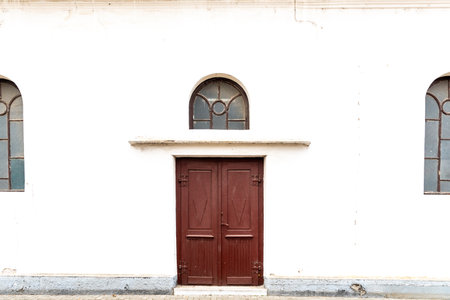 old wooden brown door in white wall of catholic churchの写真素材