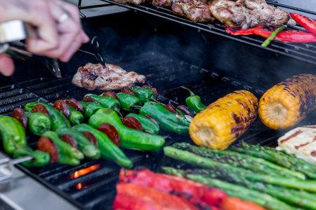 Grilling chicken, corn cobs, paprika, padron, asparagus with temperature control, meat tongs in...