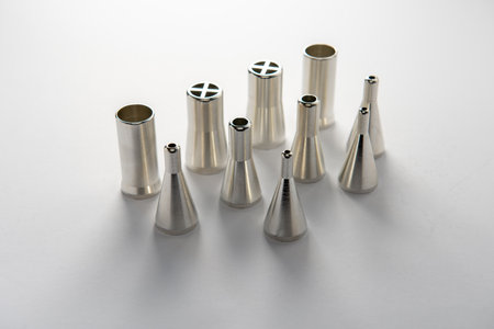 Close-up of stainless steel solder dispensing nozzles on white background, used in automated...