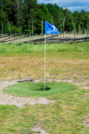 Footgolf hole with blue flag on grassy field, combining soccer and golf in a fun outdoor sport activity.の写真素材