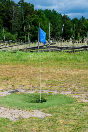 Footgolf hole with blue flag on grassy field, combining soccer and golf in a fun outdoor sport activity.の写真素材
