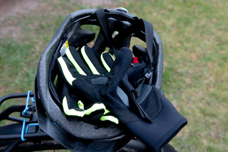 A pair of black and neon yellow cycling gloves placed inside a bicycle helmet, resting on the rear...