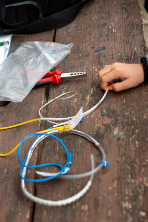 Close-up of bird ringing tools on a wooden table, including colored wires and numbered metal bands...