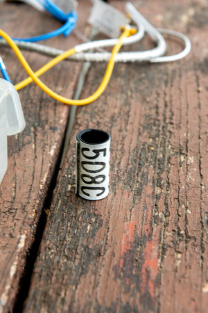 Close-up of bird ringing tools on a wooden table, including colored wires and numbered metal bands...