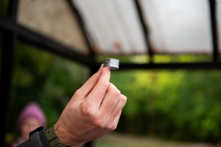 Close-up of bird ringing tool in hand, numbered metal band used for marking birds during research.の写真素材