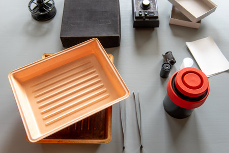 Analog photography tools including trays, film reels, a developing tank, and accessories used in traditional darkroom photo development.の写真素材