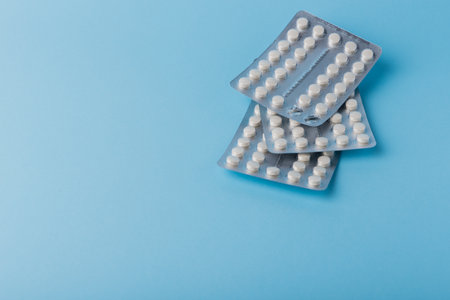 Medical background of many white capsule tablets or pills on blue table. Close up. Healthcare...
