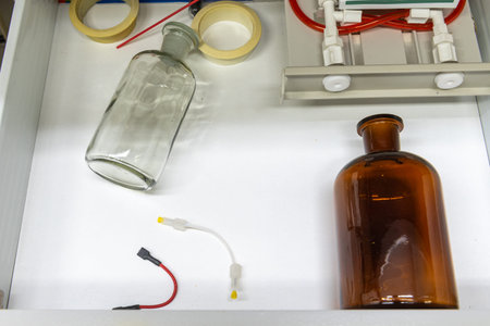 glass bottles, laboratory equipment, tubes in white drawer.