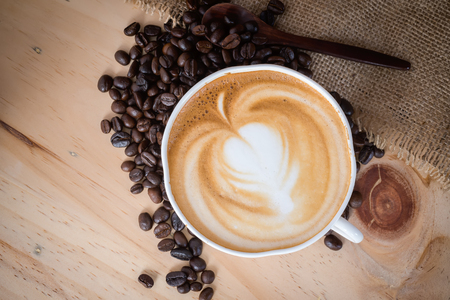 Top view of Hot cappuccino coffee on wood plate with sack fabric background.の写真素材